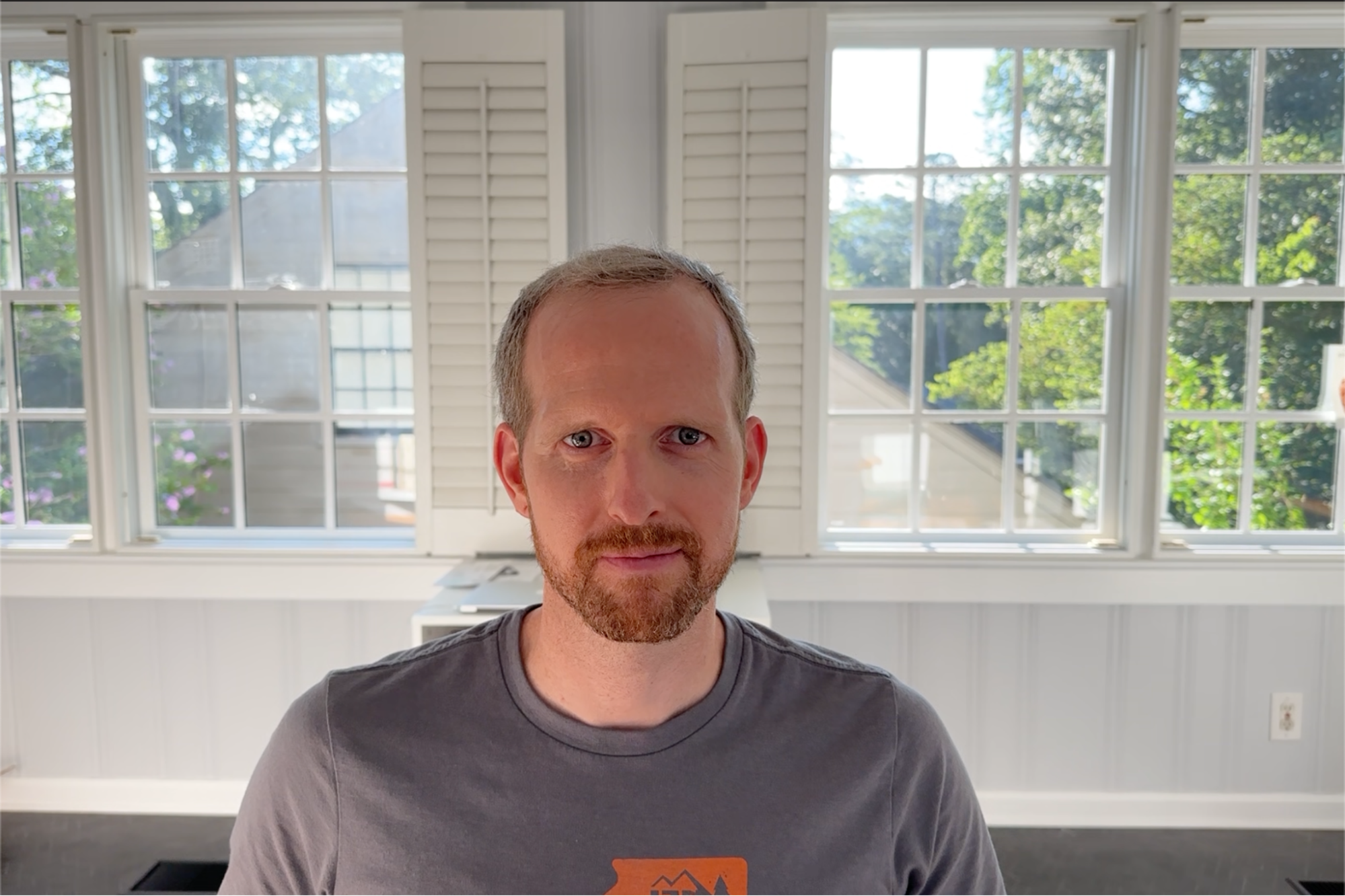 Well-lit webcam still of Mark from the shoulders up using Continuity Camera, despite strong light in the background